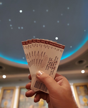 white hand holding tickets in front of Sottile Theatre dome
